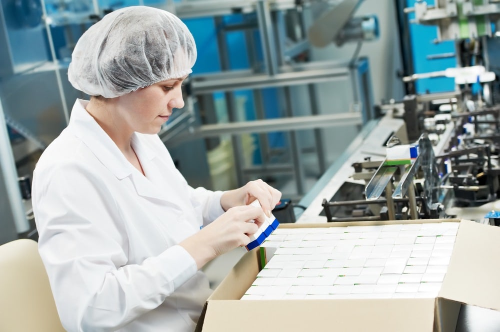 Medical Device Assembly Woman in sterile, clothing, and putting small boxes into a larger box for medical devices